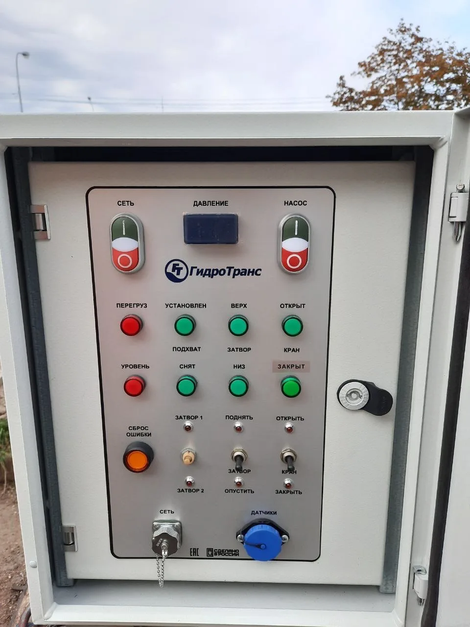 Electrical control cabinet with buttons and indicators on a panel bearing the HydroTrans logo